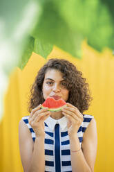 Porträt einer Frau, die eine Wassermelone isst, gelber Hintergrund - AFVF03670