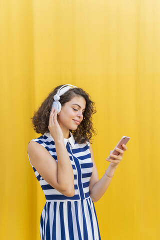 Porträt einer jungen Frau mit Kopfhörern und Smartphone, lizenzfreies Stockfoto