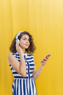 Porträt einer jungen Frau mit Kopfhörern und Smartphone - AFVF03673