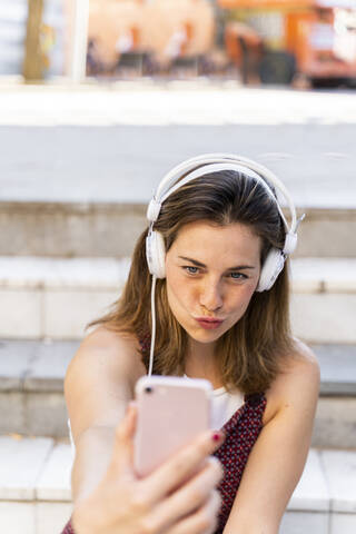 Junge Frau, die ein Smartphone benutzt, Musik hört und ein Selfie macht, lizenzfreies Stockfoto