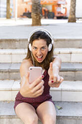 Junge Frau, die ein Smartphone benutzt, Musik hört und ein Selfie macht - AFVF03687