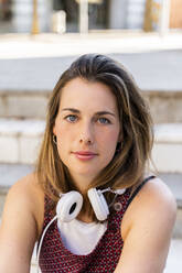 Young woman with white headphones sitting on steps - AFVF03690