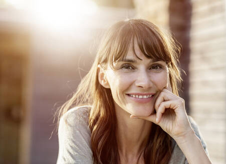 Porträt einer lächelnden brünetten Frau im Gegenlicht - FMKF05775