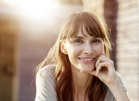 Portrait of smiling brunette woman in backlight - FMKF05775