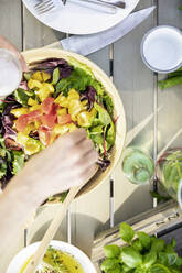 Nahaufnahme einer Frau, die einen Salat im Freien zubereitet - FMKF05801