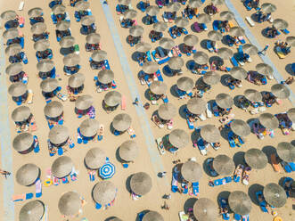 ACHAIA, GREECE - JULY 2018: Aerial view of vacationers on beach under straw parasols. - AAEF00200