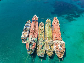 Luftaufnahme einer Luxusyacht, die mit alten Frachtschiffen im Mittelmeer vertäut ist, Nisi, Griechenland. - AAEF00228