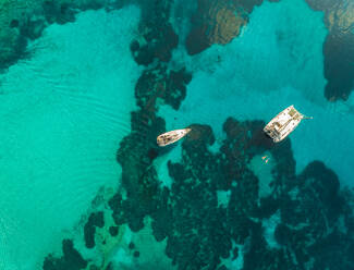 Luftaufnahme von zwei Segelbooten, die im Mittelmeer vor Anker liegen und in denen Touristen schwimmen, in der Nähe der Insel Kastos, Griechenland. - AAEF00255