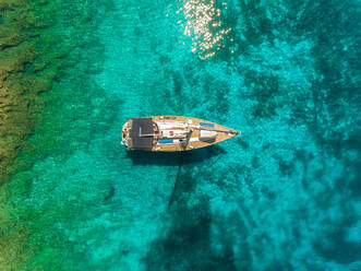 Luftaufnahme eines Segelboots, das an einer transparenten Küste vor Anker liegt, Ithaki, Griechenland. - AAEF00265