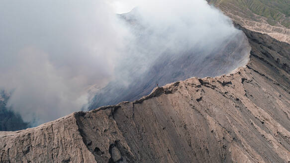 Aerial view of a man standing of the edge of mount Bromo in east of Java island, Indonesia. - AAEF00334