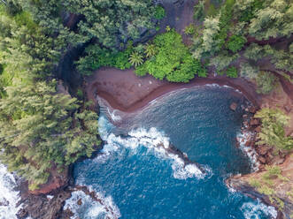 Luftaufnahme eines versteckten roten Sandstrandes, umgeben von Regenwald, Hawaii, USA. - AAEF00398