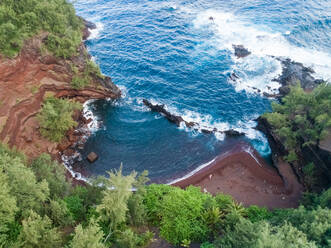 Luftaufnahme eines versteckten roten Sandstrandes, umgeben von Regenwald, Hawaii, USA. - AAEF00400