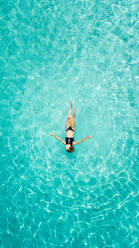 Aerial view of a woman floating in the sea of Ithaca island. - AAEF00421