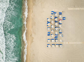 Aerial view of empty sunbeds and parasols on beach, Greece. - AAEF00434