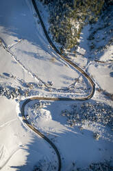 Aerial view of an empty zigzag road surrounded by snow. - AAEF00440