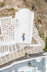 Luftaufnahme Frau auf dem Dach liegend auf Santorini traditionelles Haus mit umlaufender Treppe, Griechenland. - AAEF00469
