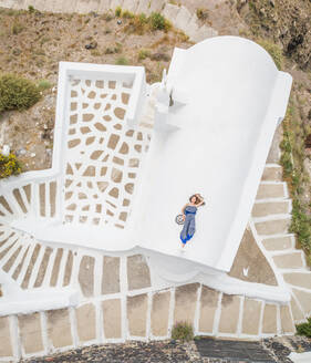 Luftaufnahme Frau auf dem Dach liegend auf Santorini traditionelles Haus mit umlaufender Treppe, Griechenland. - AAEF00470