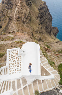 Luftaufnahme Frau auf dem Dach liegend auf Santorini traditionellen Haus mit Meer im Hintergrund, Griechenland. - AAEF00471