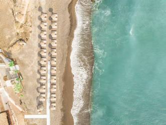 Luftaufnahme eines Strandes mit Strohsonnenschirmen auf der Insel Santorin, Griechenland. - AAEF00480