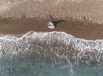 Luftaufnahme einer Frau mit Hochzeitskleid am Strand der Insel Santorin, Griechenland. - AAEF00484