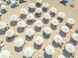 Luftaufnahme eines Strandes mit weißen Sonnenschirmen auf Achaia, Griechenland. - AAEF00497