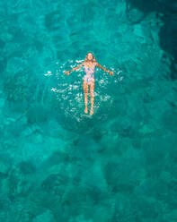 Aerial view of a attractive young woman in swimsuit floating in the sea off Atokos island, Greece - AAEF00500