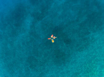 Luftaufnahme von vier Freunden, die auf aufblasbaren Matratzen auf der Insel Atokos, Griechenland, schwimmen. - AAEF00504