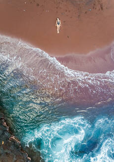 Aerial view of an attractive woman sunbathing on red sand beach, Hawaii, U.S.A. - AAEF00651