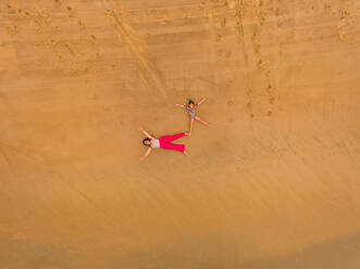 Luftaufnahme von zwei Mädchen, die sich am Strand in Cajueiro, Brasilien, vergnügen - AAEF00729
