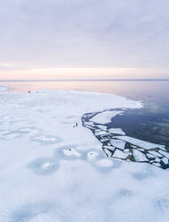 Luftaufnahme eines Mannes, der mit seinem Hund auf dem zugefrorenen Meer in Muraste, Estland, spazieren geht. - AAEF00880