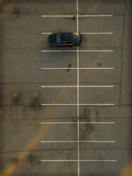 Aerial view of a car parked alone in a parking with sunset lights. - AAEF00909