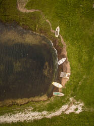 Luftaufnahme eines kleinen Holzbootes, das an einem kleinen Strand auf der Insel Vormsi in Estland vertäut ist. - AAEF01015