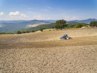 Tractor plowing in farm against sky, Italy - WPEF01678