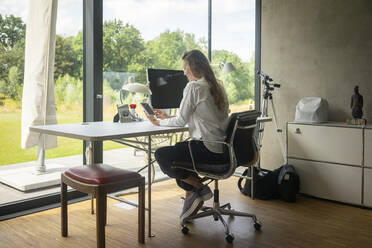 Geschäftsfrau arbeitet am Schreibtisch zu Hause - MOEF02393