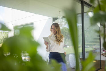 Smiling businesswoman using tablet in modern home - MOEF02407