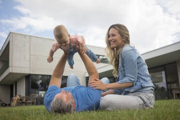 Happy father with mother lifting up baby girl in garden - MOEF02426