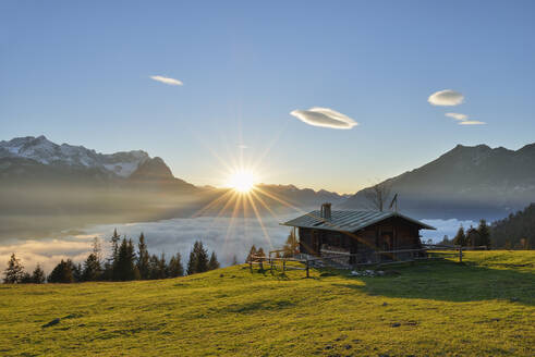 Blick auf die Blockhütte auf der Wank Zugspitze gegen die Wolkenlandschaft bei Sonnenuntergang in Bayern, Deutschland - RUEF02303