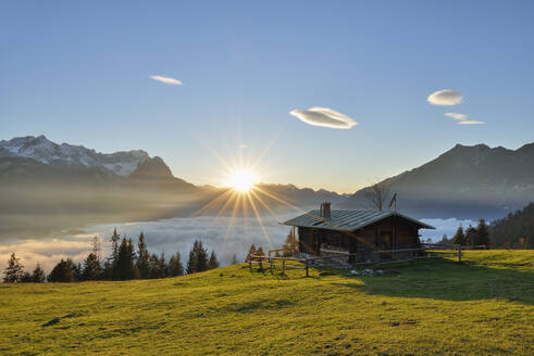 View of log cabin at Mt. Wank Zugspitze against cloudscape during sunset in Bavaria, Germany - RUEF02303