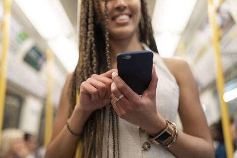 Happy woman looking at cell phone in underground train, London, UK stock photo