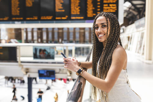 Porträt einer glücklichen jungen Frau am Bahnhof, London, UK - WPEF01701