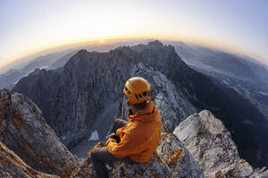 Bergsteiger mit orangefarbenem Helm bei Sonnenaufgang auf der Ellmauer Halt, Wilder Kaiser, Ellmauer Halt, Tirol, Österreich - CVF01444