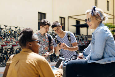 Students meeting in a backyard, talking, unsing smartphones - SODF00058