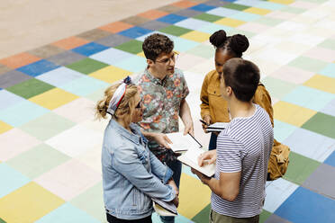 Students standing in backyrad, discussing, holding books - SODF00067