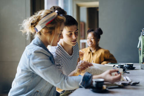 Schüler treffen sich im Café, lernen gemeinsam, nutzen Laptop und Smartphones - SODF00069