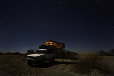 Tent on off-road vehicle on field against sky, Makgadikgadi Pans, Botswana - VEGF00452