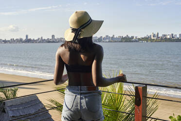 Junge Frau an der Uferpromenade mit Blick auf die Skyline von Maputo, Mosambik - VEGF00455