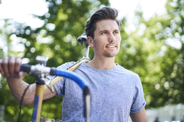 Porträt eines Mannes, der ein Fahrrad auf seinen Schultern trägt - PNEF01813
