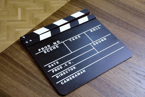 High angle view of film slate on wooden table - AXF00830