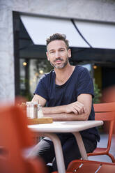 Smiling mature man sitting at street cafe - PNEF01841