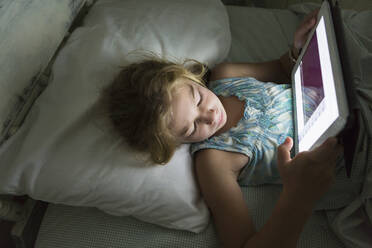 Kaukasisches Mädchen benutzt Tablet-Computer im Bett - BLEF13754